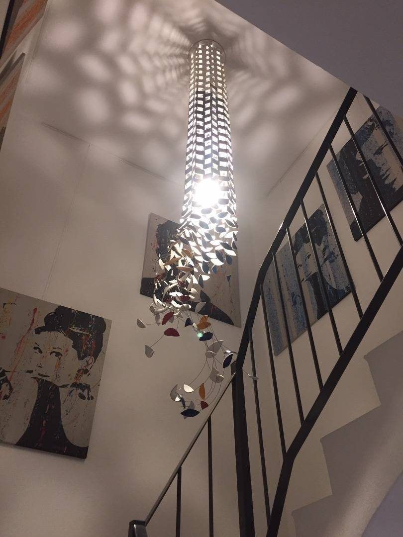 Passage secret - Métropolis, projet de Sète. Réalisation d'une sculpture lumineuse de notre collection Métropolis, pour un coeur d'escalier et tombant du plafond. Les couleurs reprennent l'ambiance colorée de la décoration de la cage d'escalier.