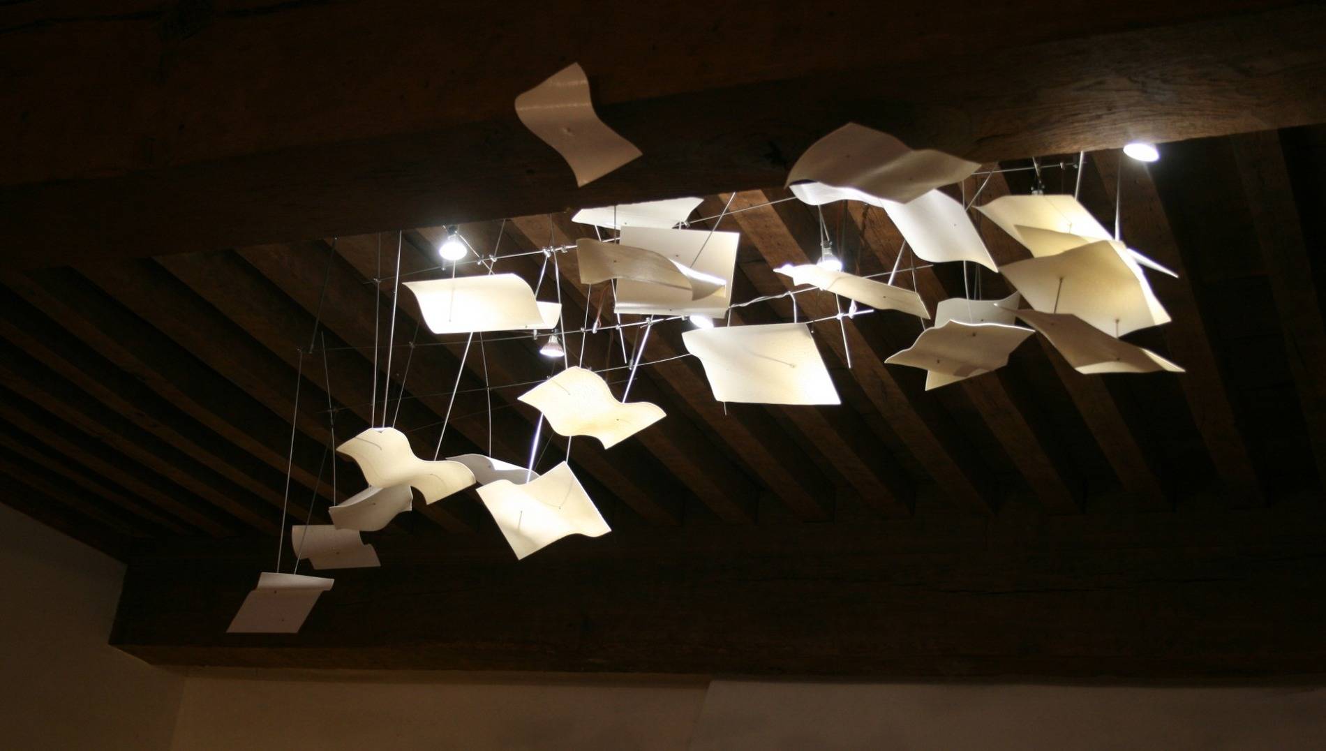 Passage secret - suspension Envolée en porcelaine papier blanche et structure inox. Réalisée pour une salle à manger, chez un particulier libraire de métier.