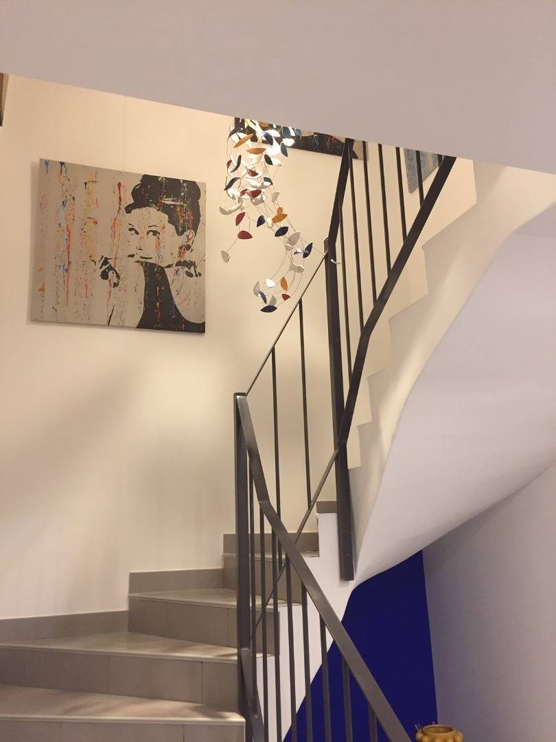 Passage secret - Métropolis, projet de Sète. Réalisation d'une sculpture lumineuse de notre collection Métropolis, pour un coeur d'escalier et tombant du plafond. Les couleurs reprennent l'ambiance colorée de la décoration de la cage d'escalier.